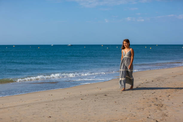 WOMAN WALKING ON THE SAND OF THE BEACH Young woman walking nude foots on the sand of the beach. Joy and freedom concept. mistral wind stock pictures, royalty-free photos & images