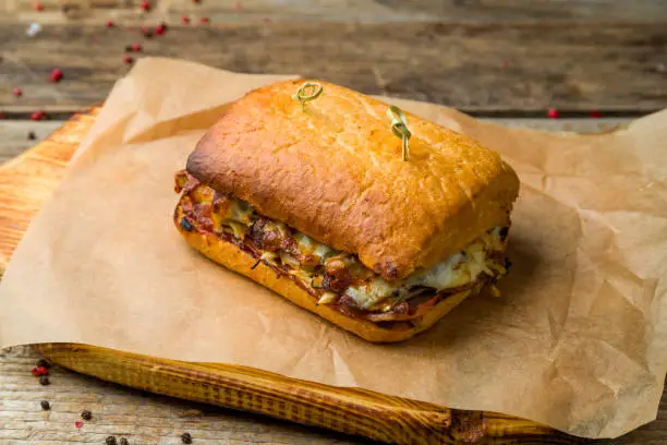 Photo of meat sandwich with ciabatta on old wooden table