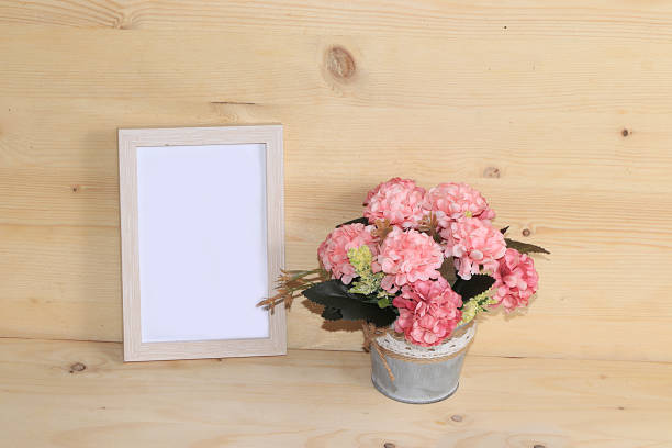 istock Potted flowers and frame for text on a wooden background, home office. Creative modern bouquet, minimal holiday concept. Greeting card for Women's Day or Mother's Day 1216672332