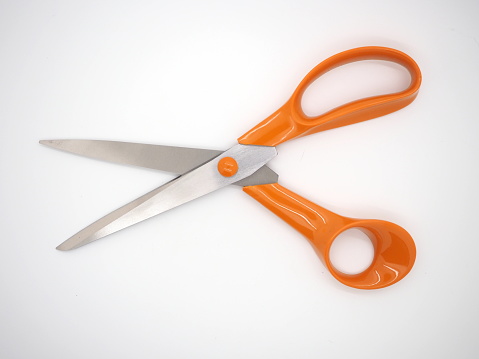 A pair of multipurpose scissors with stainless steel blades and orange coloured handles on a white background.