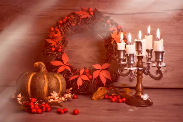 Autumn wreath and still life with ancient candelabrum candle stick, candles, flame. Wooden mushrooms, berries on wood. Design for seasonal Fall birthday or anniversary card, toned image with flare.