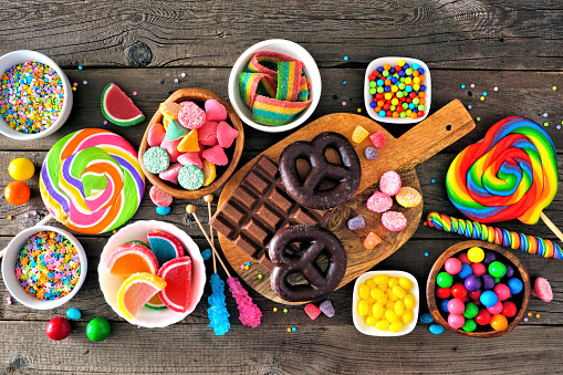 Colorful sweet candy buffet table scene. Above view over a rustic wood background.