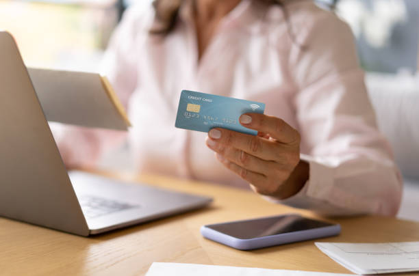 istock Unrecognizable woman at home paying bills online using credit card 1216674024