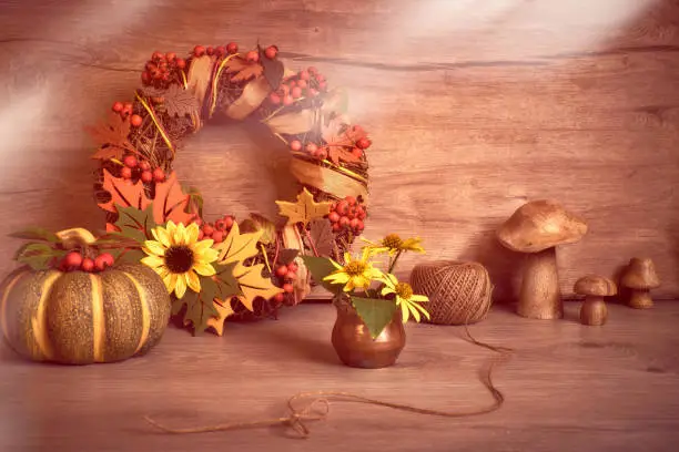 Autumn Thanksgiving arrangement with ceramic pumpkins, wooden mushrooms, natural yellow flowers. Decorative wreath with Fall leaves, felt decorative elements and berries. Copy-space