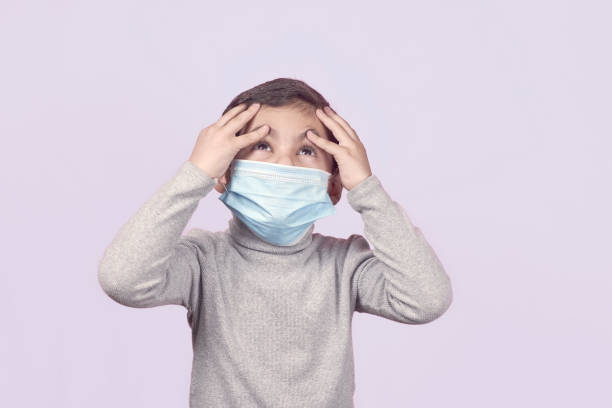 istock A sick boy in surgical mask haves headache 1216674911