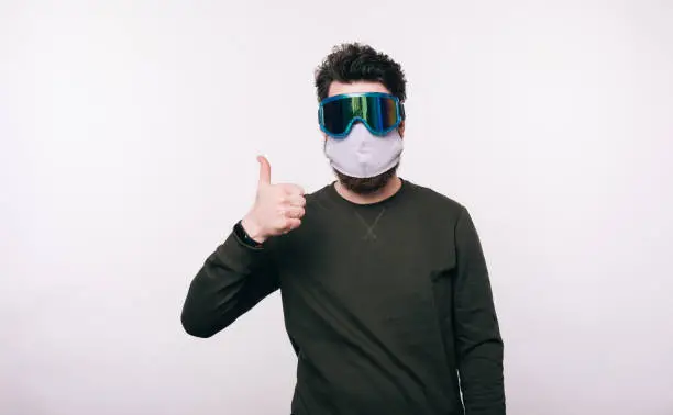 Photo of man with facial mask  showing thumbs up over white background