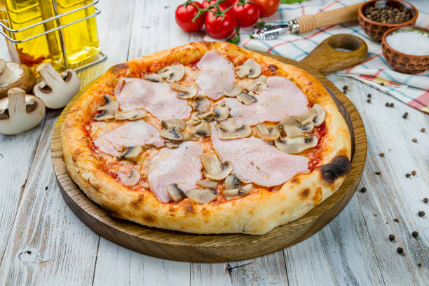 istock Pizza with ham and mushrooms on white wooden table 1216678437