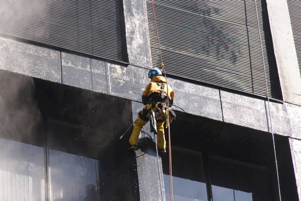 Construction worker power washes windows one of the office buildings in Downtown Vancouver stock photo
