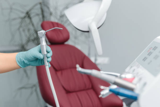 kobieca ręka dentysty w niebieskich rękawiczkach trzymająca strzykawkę z wodą powietrzną nad niewyraźnym tłem kliniki z oddziałem stomatologicznym. stomatologia i pielęgnacja zębów z kopią przestrzeni - air needle zdjęcia i obrazy z banku zdjęć