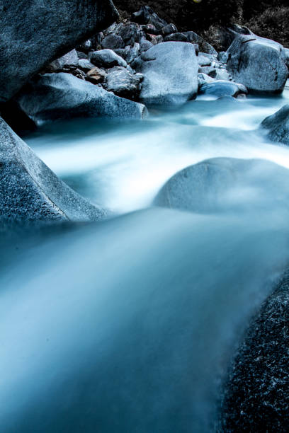 istock High mountain stream flows over green rocks in rugged environment 1216681340