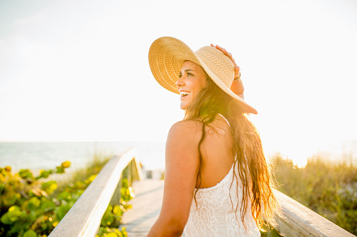 Female Latina showing positive emotion while walking towards the beach. Lifestyle image with happy emotions.