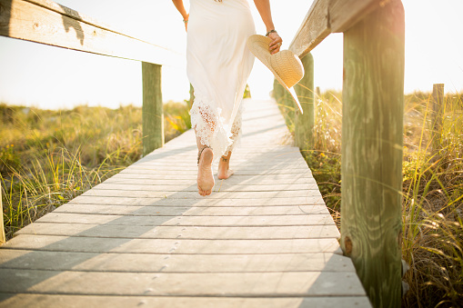 Detail of a woman walking towards the beach. Relaxin lifestyle image of a tourist on her vacation.