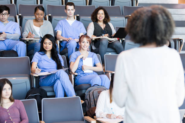 Professor teaches a class of medical students A class of attentive medical students listen to a mature female professor's lecture. medical education stock pictures, royalty-free photos & images