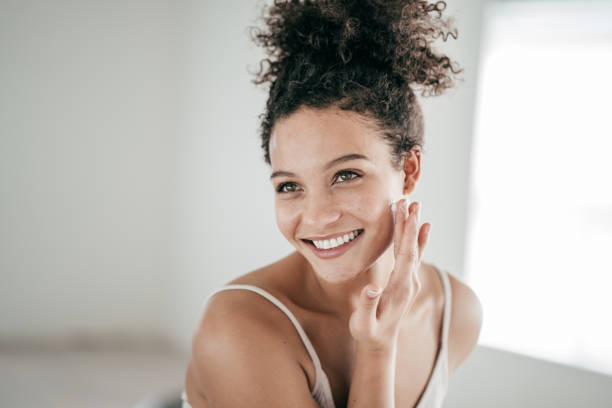istock Smiling young women applying moisturiser to her face 1216688516