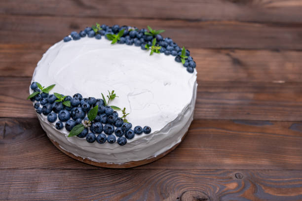 istock Appetizing cheesecake cake biscuit pillow decorated white cream blueberries and mint stands on wooden rustic table 1216688597