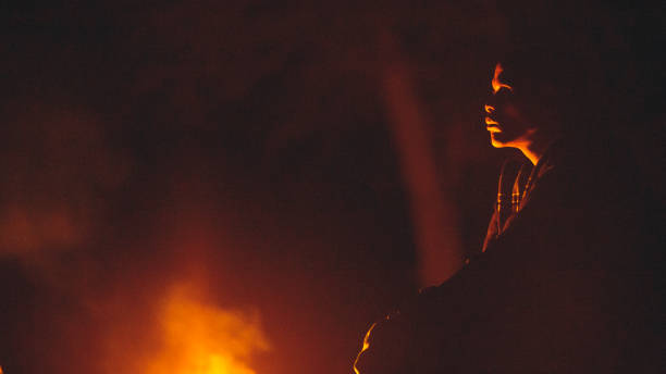 bushman del botswana della tribù indigena di san che guarda un fuoco bruciare - boscimani foto e immagini stock