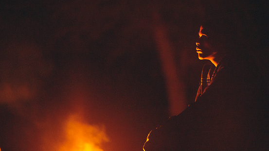 Botswana Bushman from San indigenous tribe watching a fire burn