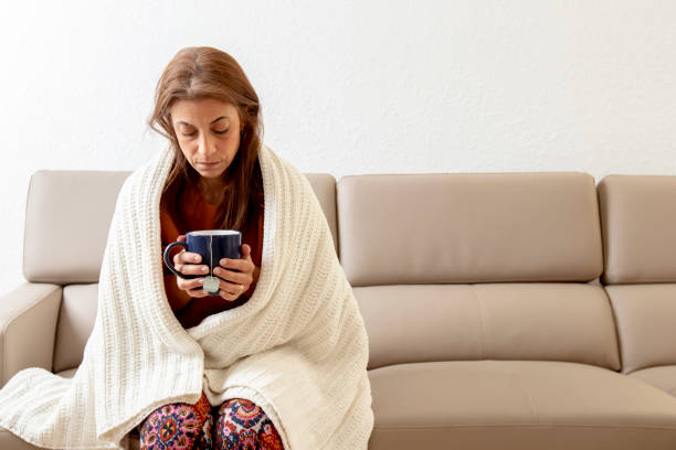 istock Sick woman on couch drinking tea 1216690488
