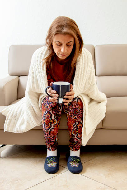 istock Sick woman on couch drinking tea 1216690543