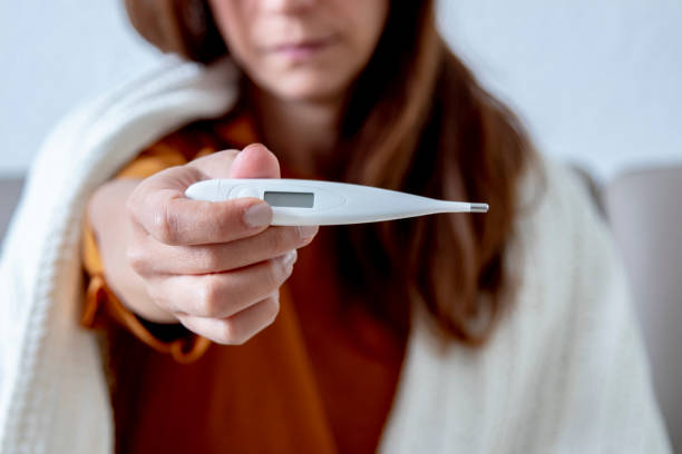 istock Sick woman on couch checking temperature 1216690562