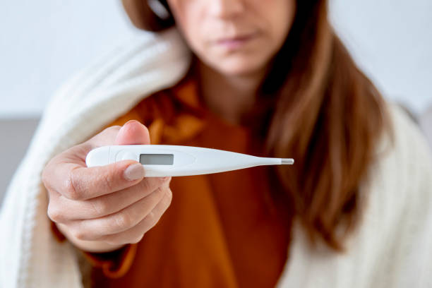 istock Sick woman on couch checking temperature 1216690597