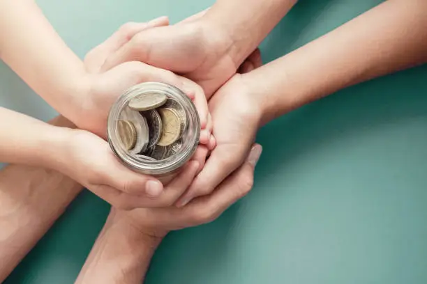 Photo of child and parent hands holding money jar, donation, saving, charity, family finance plan concept, Coronavirus economic stimulus rescue package, superannuation concept