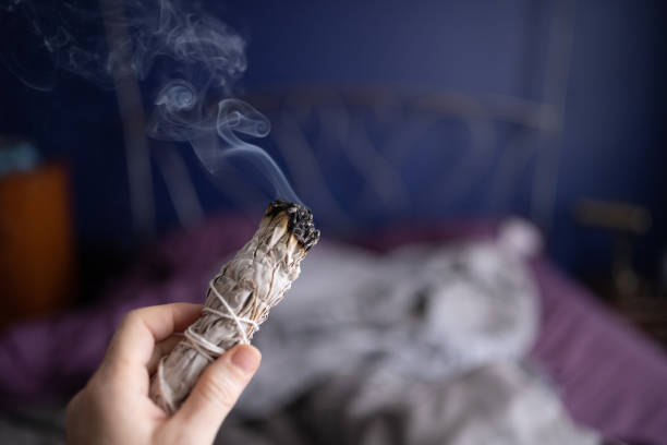 woman cleansing the air by smudging burning sage indoors in miami florida - burning incense imagens e fotografias de stock