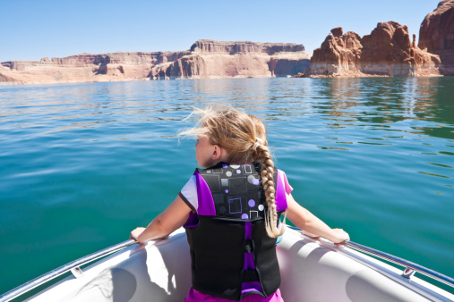 A young girl looking out on the front of a boat at beautiful Lake Powell National Recreation Area