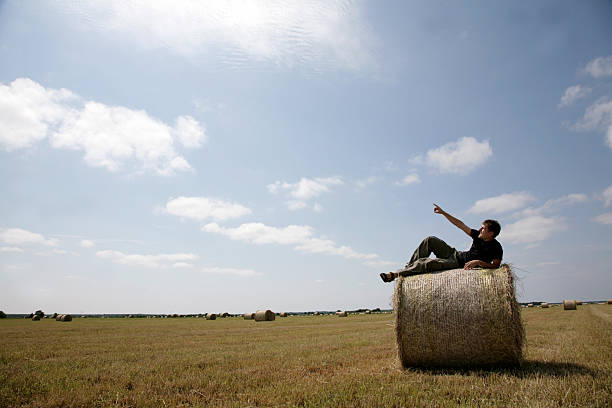istock man lying on bale of hay in field 121671477