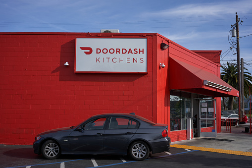 Redwood City, CA, USA - Feb 16, 2020: A driver waits in his car for food delivery pickup outside a DoorDash Kitchens location. DoorDash provides customized kitchen space for restaurant operations offering delivery and pickup services through DoorDash's app.