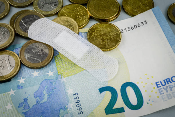 economía enferma. concepto para el desastre económico de la pandemia del coronavirus. una ayuda de banda (yeso medicado) para fijar monedas en euros. - adhesive bandage currency finance repairing fotografías e imágenes de stock