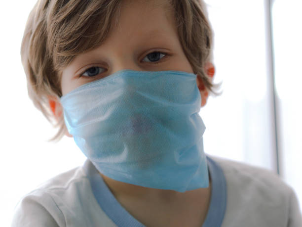 istock protection against coronavirus. little boy puts a mask on her face. 1216728481