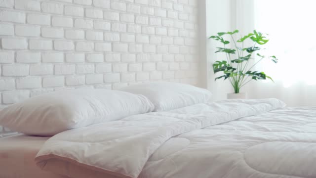 bed with white pillow and blanket with natural light in bedroom in the morning,bed and Cozy Bedroom Concept
