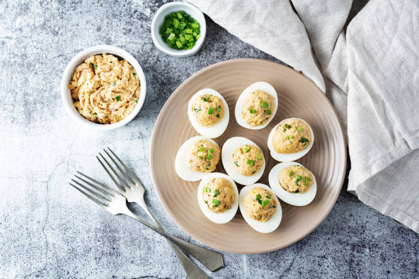 Canned Tuna deviled eggs with scallion on a light background stock photo
