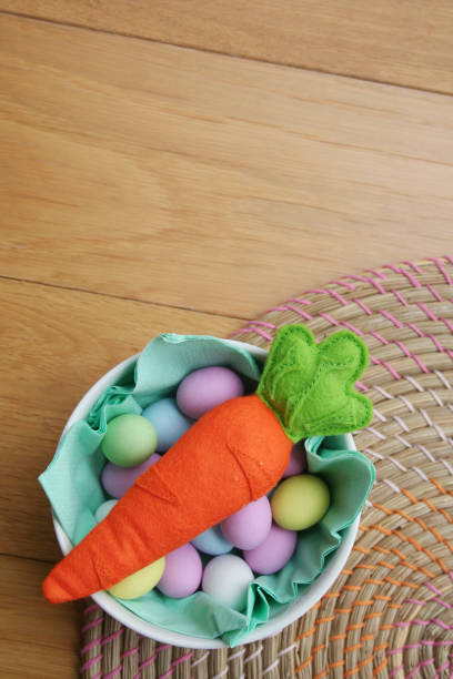istock Carrot made by felt with on a bowl full of colorful sugar Easter eggs 1216735598