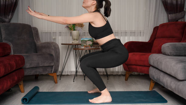 Young woman does exercises from home during quarantine time stock photo