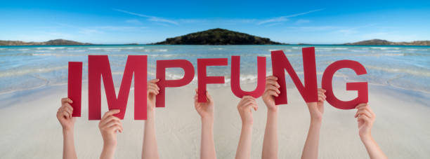 istock People Hands Holding Word Impfung Means Vaccination, Ocean Background 1216738090