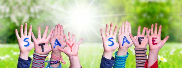 istock Kids Hands Holding Word Stay Safe, Grass Meadow 1216740053
