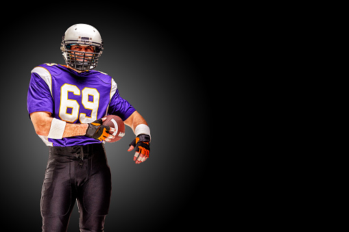 American football player posing with ball on black background. championship game concept. Concept American football, portrait American, Motivator. Black white background, copy space