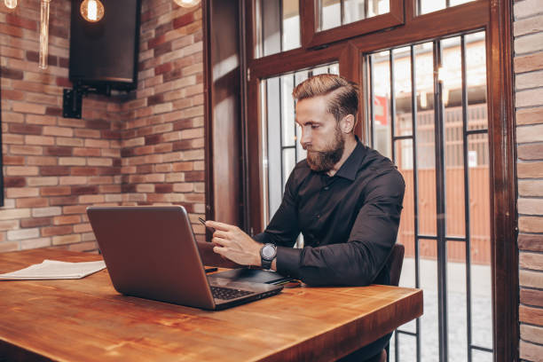 istock Young businessman texting on smart phone and working on a laptop while sitting in cafe 1216742967