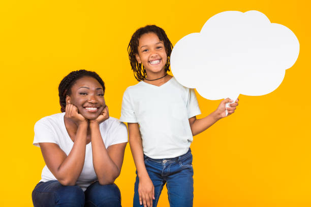Happy family holding white speech bubble at yellow studio