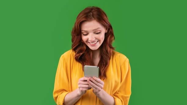 istock Girl Using Smartphone Texting With Friends Online Standing In Studio 1216748302