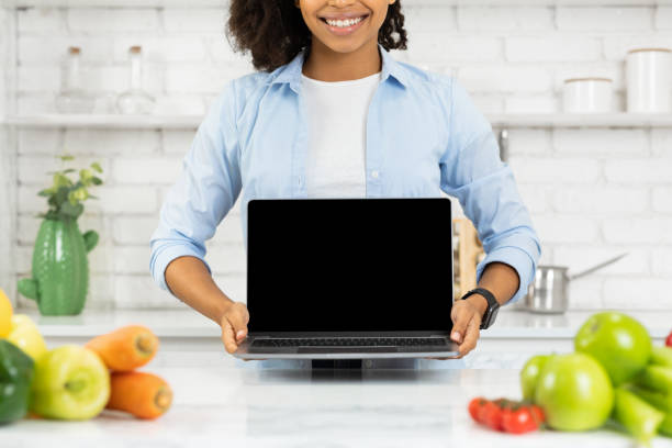 istock Unrecognizable afro girl holding laptop in the kitchen 1216748831