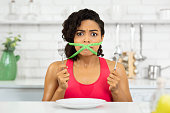Afro woman with green measuring tape around her mouth