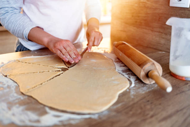 Photo of woman making a dough in kitchen. Adult woman lady housewife baker holding knife in the kitchen table. Baking pastry concept cooking cake biscuit doing bakery making homemade pizza at home.