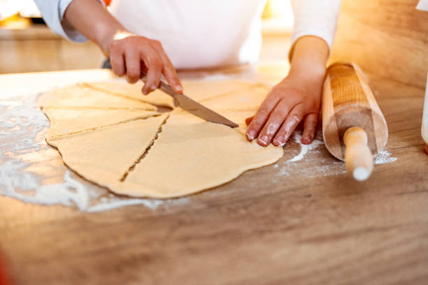 istock Hand cuts rolled raw curd dough with a round pizza knife into eight triangles 1216749554