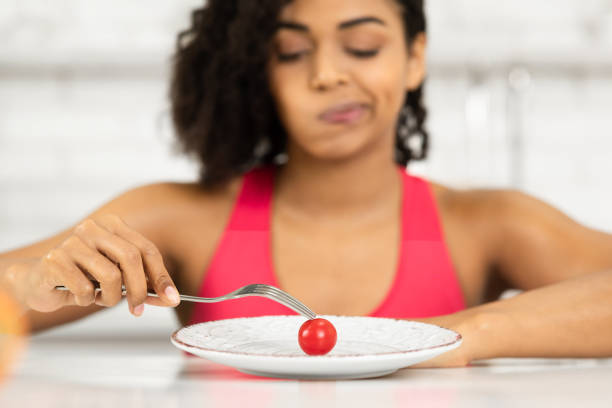 istock Afro woman looking at tiny tomato on a plate 1216749982