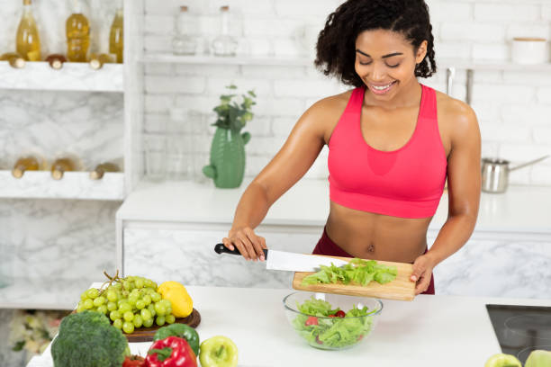 istock Beautiful young black girl preparing vegetable salad 1216750128