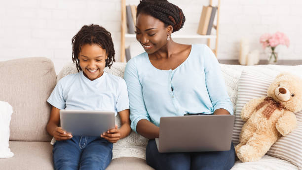 istock Afro mom and daughter using laptop and tablet 1216751265