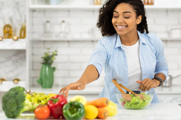 istock Happy young afro girl preparing vegetable salad 1216751299